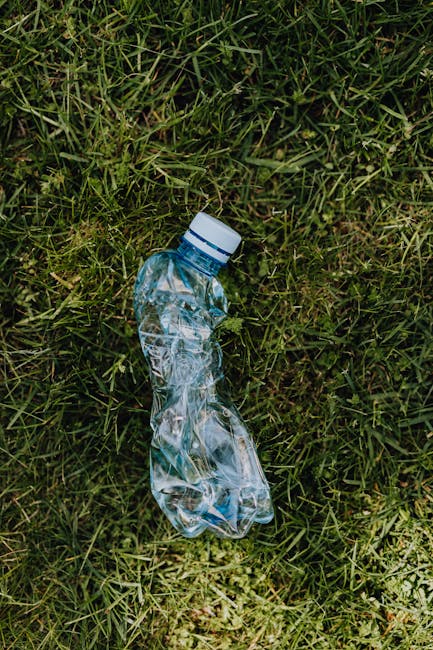A clear visual image shows a collection of various discarded household waste materials piled on a gravel driveway in an outdoor setting. The waste includes black plastic trash bags, some partially tor